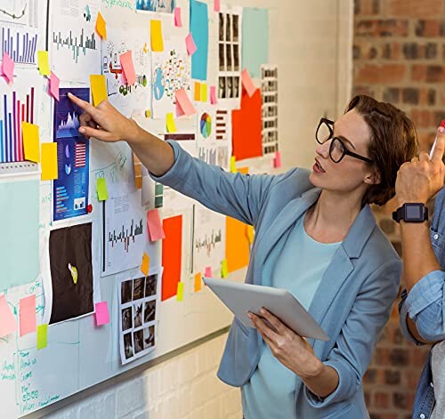 Businesswoman pointing at graphs on a board during a brainstorming session.