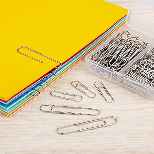 Stack of colorful papers with paperclips and a box of paperclips.