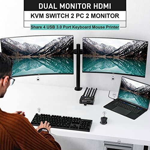 Person using dual monitor KVM switch with laptop and desktop.