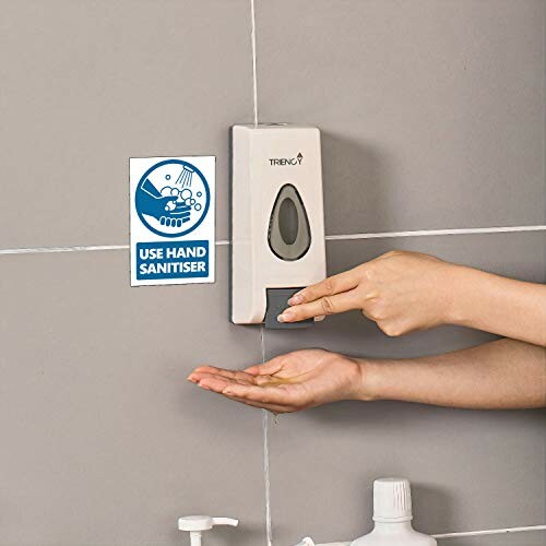 Person using hand sanitizer dispenser on wall.