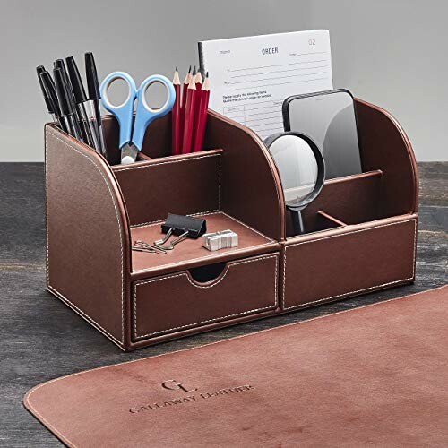 Leather desk organizer with office supplies like pens, scissors, and notepads.