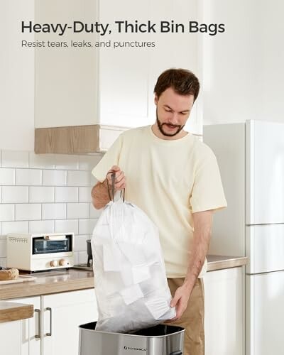 Man placing a thick bin bag into a trash bin in a kitchen.