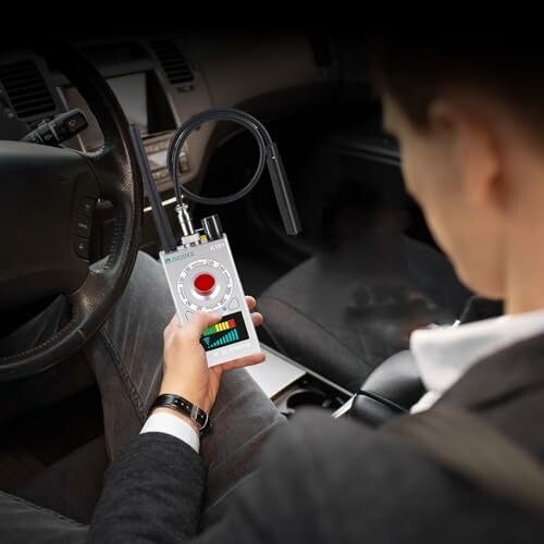 Man holding a device inside a car.