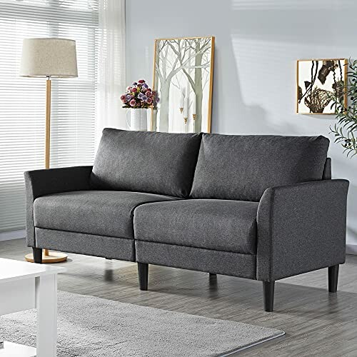 Modern gray sofa in a living room with a floor lamp and decorative wall art.