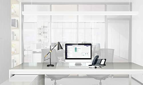 Modern office desk with computer, lamp, and phone.