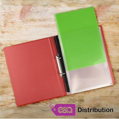 Open red binder with green folder inside on wooden surface