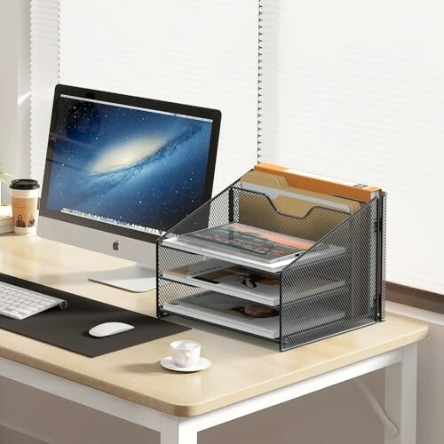 Office desk with computer, coffee cup, and file organizer.