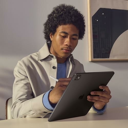 Person using a tablet with a stylus at a desk.