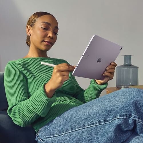 Woman in green sweater using a tablet with a stylus.